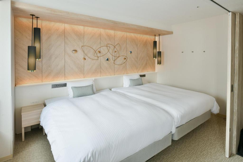 a bedroom with a white bed and wooden cabinets at Vessel Hotel Campana Nagoya in Nagoya