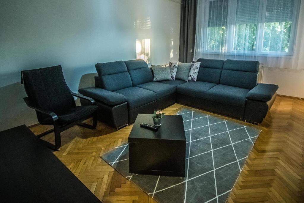 a living room with a blue couch and a chair at Főtér Apartman in Szarvas