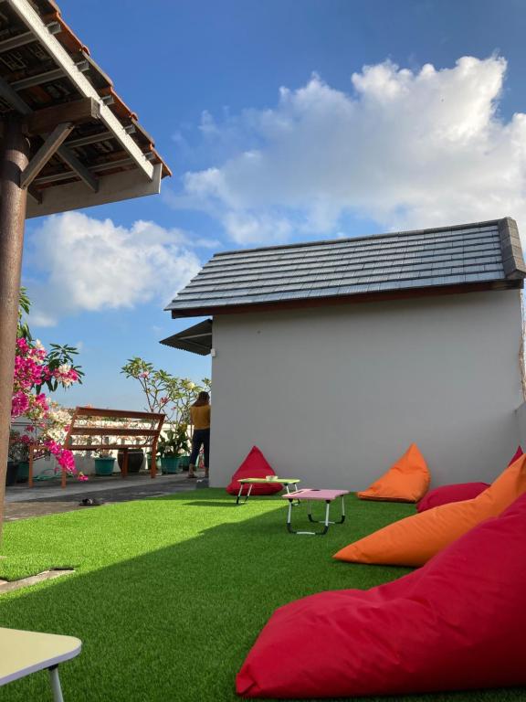 d'une terrasse avec de l'herbe verte et des oreillers rouges. dans l'établissement Rumahku Bali Executive, à Kuta