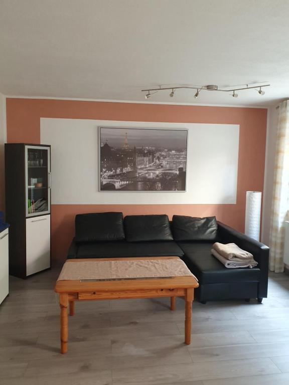 Sala de estar con sofá negro y mesa de centro en Ferienwohnung-Pera, en Andernach