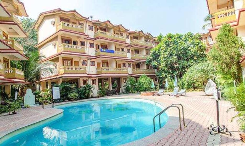 a large building with a swimming pool in front of it at Hotel Toro Highland Beach Resort With Pool - 500M From Candolim Beach in Candolim