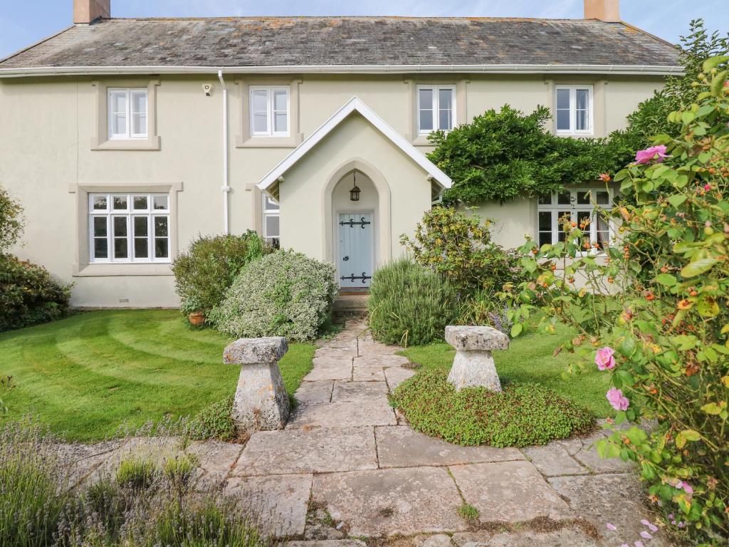 a house with a garden with two stone statues in the yard at Crablake Farmhouse in Exeter