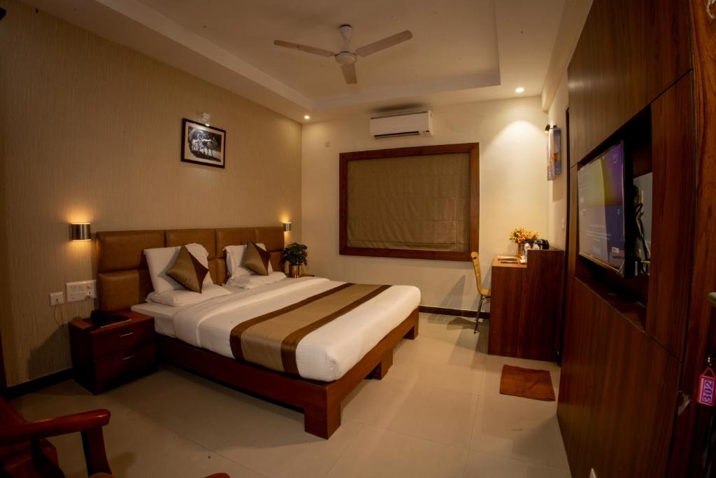 a bedroom with a bed and a flat screen tv at Metro Plaza Hotel in Mangalore