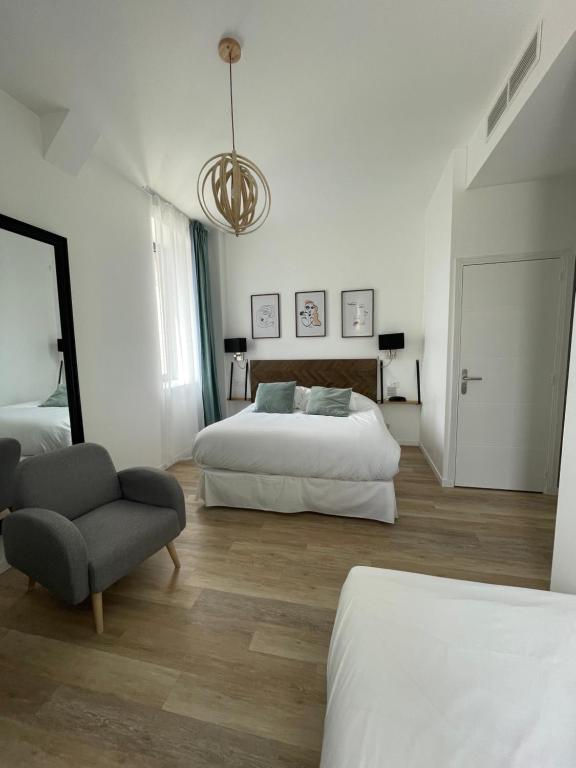 a white bedroom with two beds and a chair at LA TOUR AUX CRABES près de la plage in Dieppe