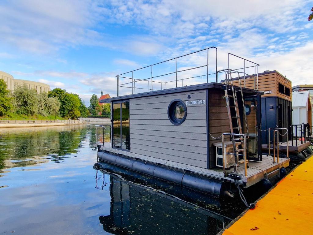 una pequeña casa en un barco en un río en Dom na wodzie LaMare XS 2 en Bydgoszcz