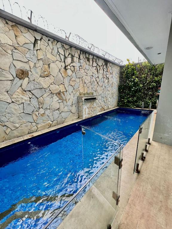 a swimming pool with a stone wall and blue water at Kebagusan Park Residence in Jakarta