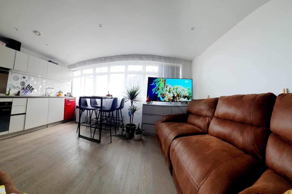 a living room with a brown couch and a kitchen at Luxury 1 bed apartment-sea view in Bournemouth