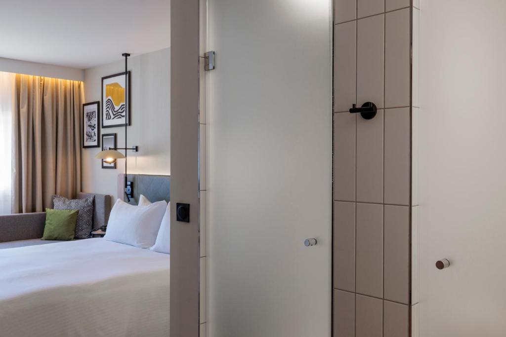 a hotel room with a bed and a shower at Hilton Garden Inn Marseille Provence Airport in Marignane