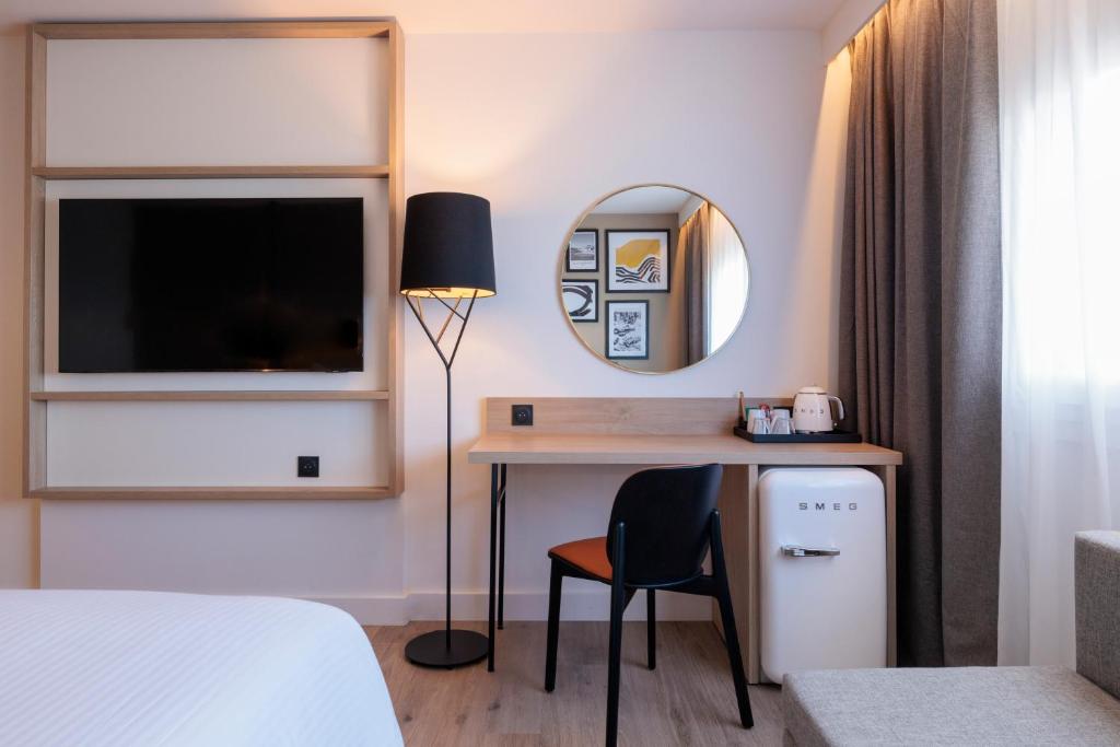 a hotel room with a desk and a mirror at Hilton Garden Inn Marseille Provence Airport in Marignane