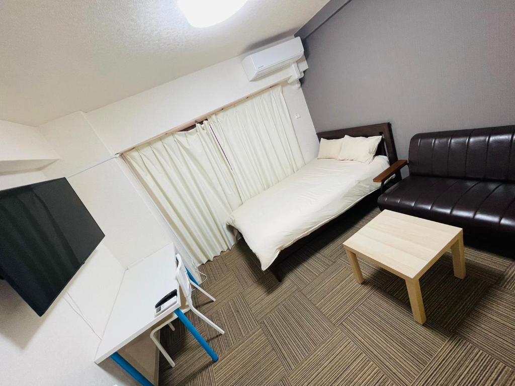 ein kleines Zimmer mit einem Sofa und einem Tisch in der Unterkunft DAIKAN YOKOSUKA l 横須賀中央 in Kusugaurachō
