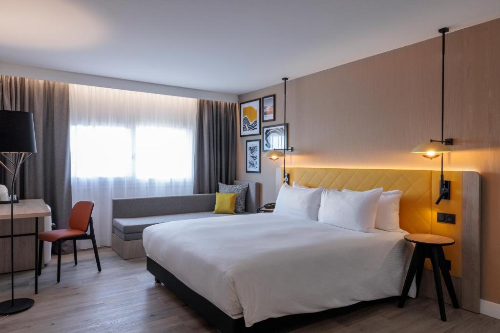 a hotel room with a large bed and a couch at Hilton Garden Inn Marseille Provence Airport in Marignane