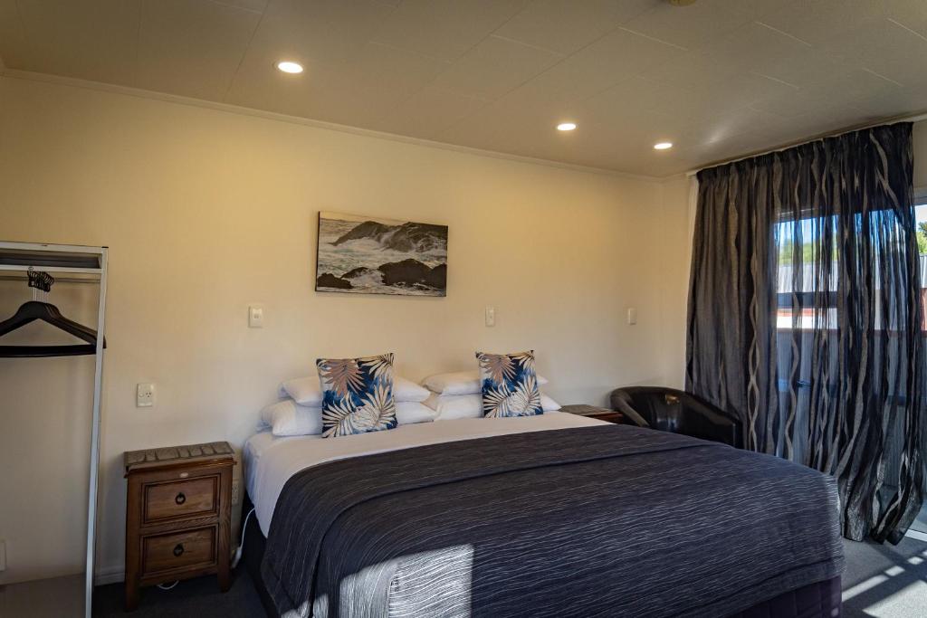 a bedroom with a large bed and a window at Amber Court Motel in Te Anau