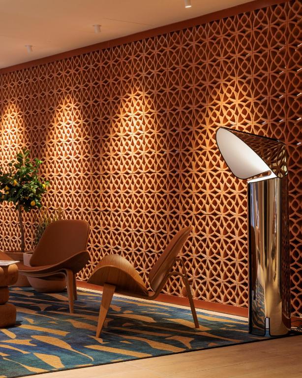 a lobby with a patterned wall with two chairs and a lamp at Hilton Garden Inn Marseille Provence Airport in Marignane