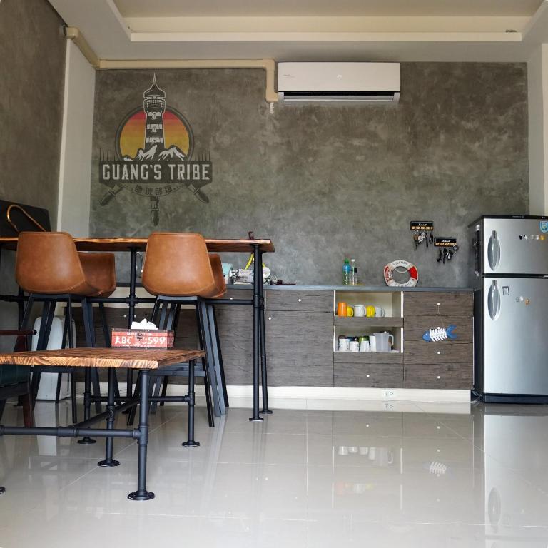 a kitchen with a bar with chairs and a refrigerator at Guang's Tribe Homestay in Magong