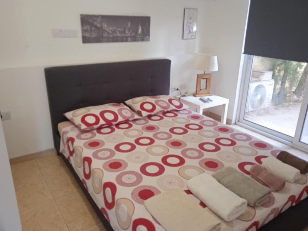 Nicosia rest and relax 1 bedroom apartment في نيقوسيا: غرفة نوم مع سرير وملاءات حمراء وبيضاء ونافذة
