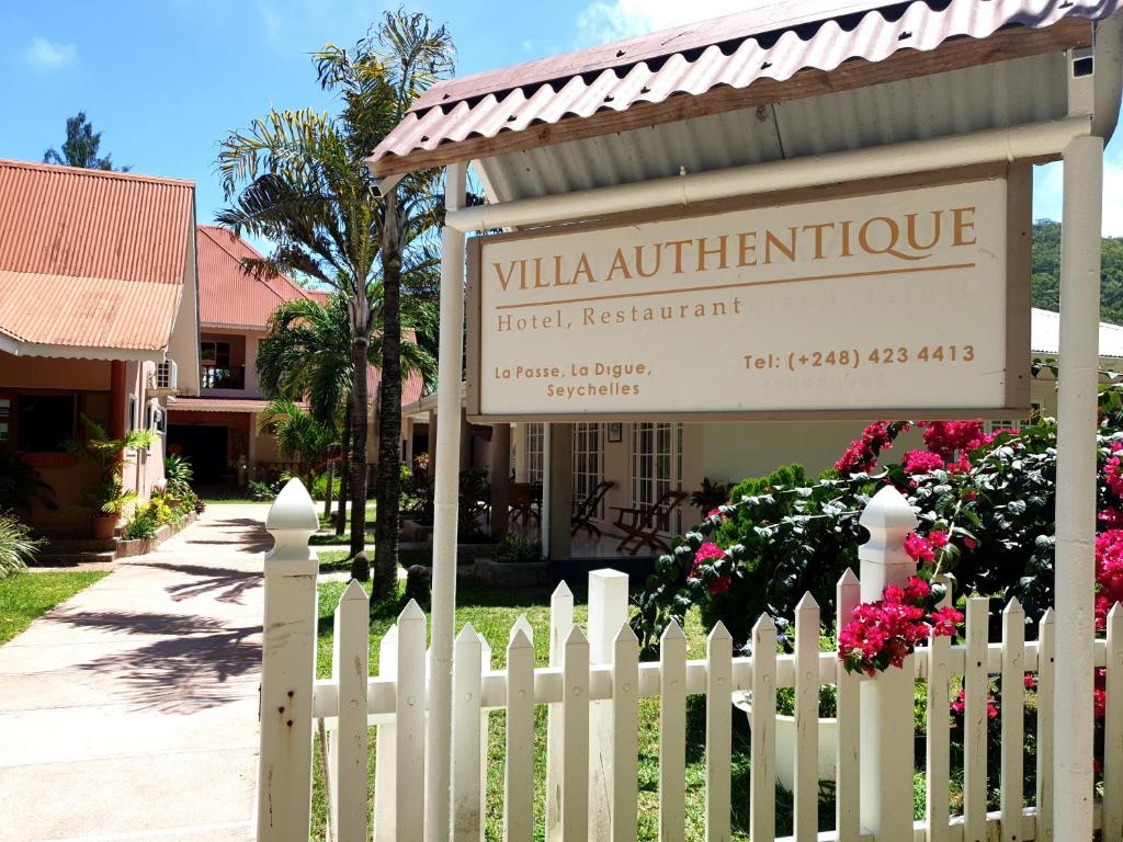 une clôture blanche devant un hôtel avec un panneau dans l'établissement Villa Authentique, à La Digue