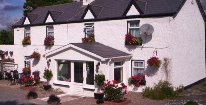 Castlemaine House B&B في كاستلماين: البيت الأبيض مع الزهور أمامه