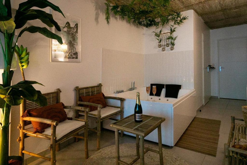 una sala de estar con sillas y una mesa con una botella de vino en Bali Serenity Balnéo et lit rond, en Lagnieu