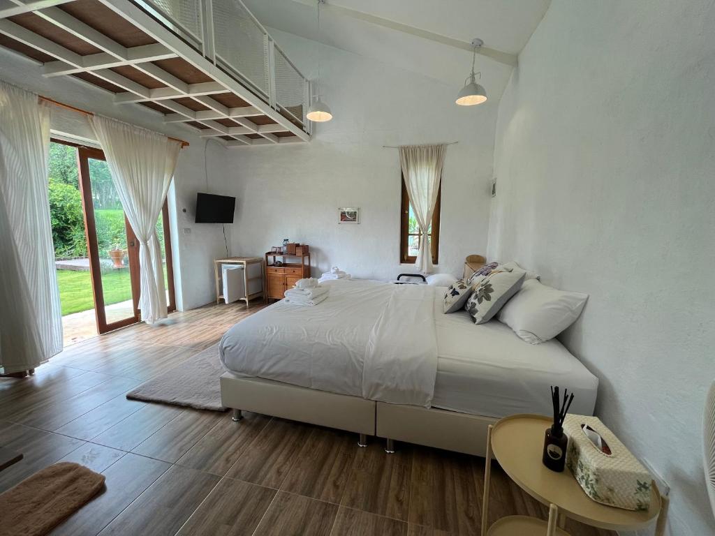 een witte slaapkamer met een groot bed en een tafel bij The Little Clay House (Huahin) in Ban Thap Tai (1)