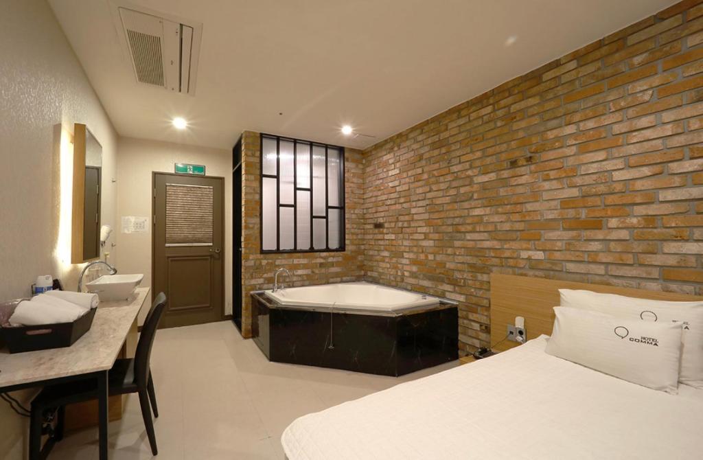 a bedroom with a bath tub and a brick wall at Nampo Comma Hotel in Busan