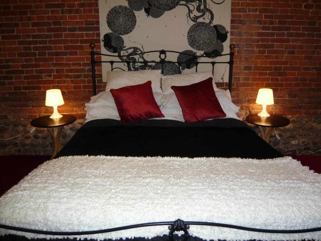 a bedroom with a bed with red pillows and two lamps at Seafret Barn 4 plus 2 in Roughton
