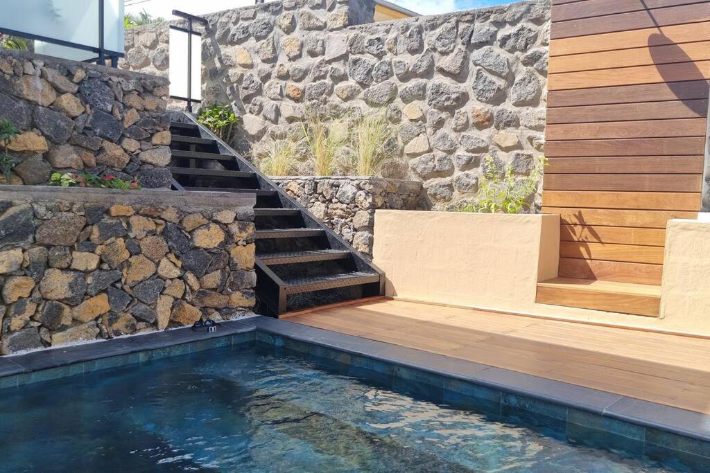 a swimming pool with stairs and a stone wall at Villa standing 52 in Ravine des Cabris