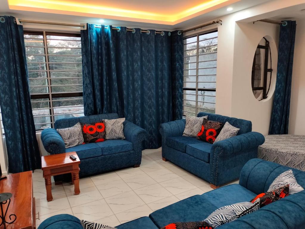 una sala de estar con sofás y ventanas azules. en Kesuiyo Loft en Nairobi