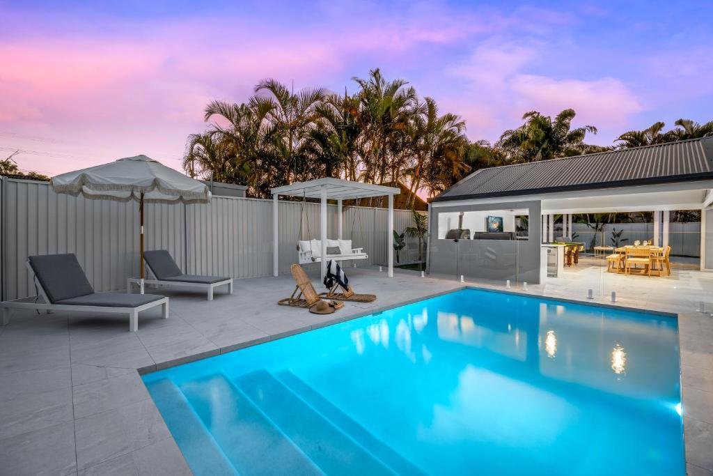 a swimming pool with a patio and a house at Paradise Palms Mooloolaba - Beach House in Mooloolaba