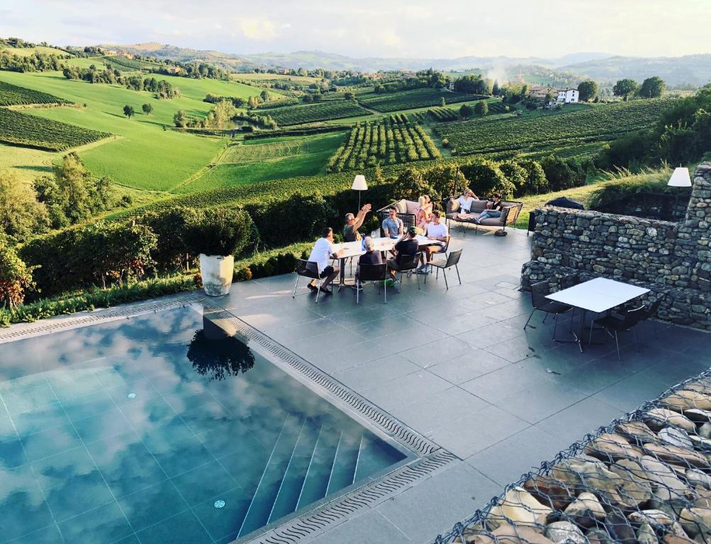 a group of people sitting at a table near a swimming pool at Agriturismo Opera 02 in Castelvetro di Modena