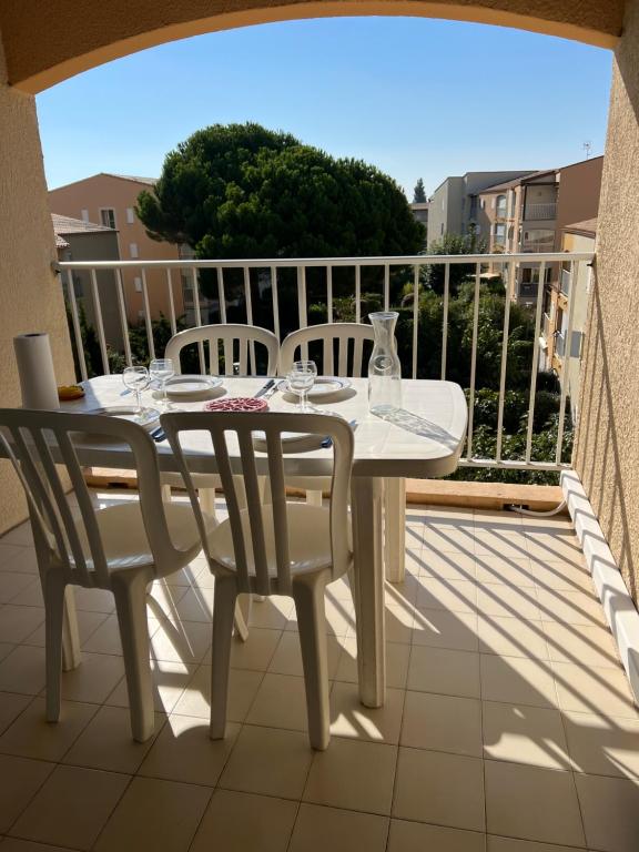 d'une table et de chaises blanches sur un balcon. dans l'établissement JEAN BART III Joli T2 cabine mezzanine proche plage Richelieu Cap d'Agde, au Cap d'Agde