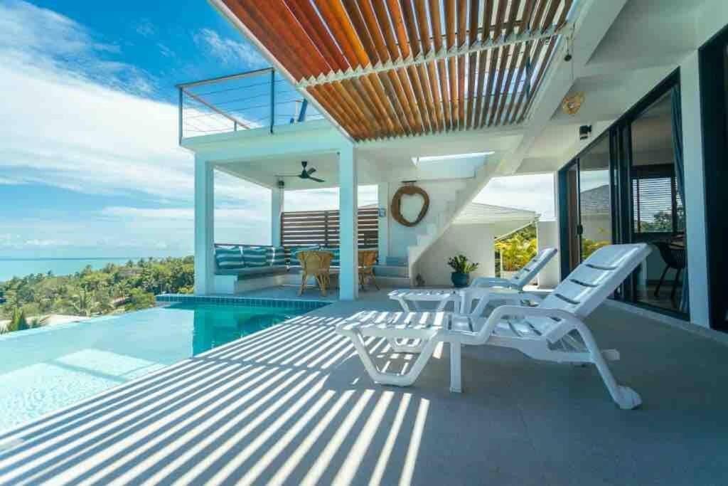 un patio con sillas blancas y una piscina en 3 Bedrooms sea view villa, en Haad Yao