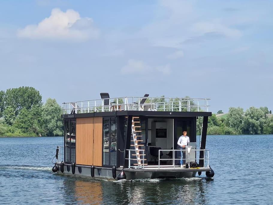 a man on a tiny house boat on the water at Tiny Houseboat Luxery in Zeewolde