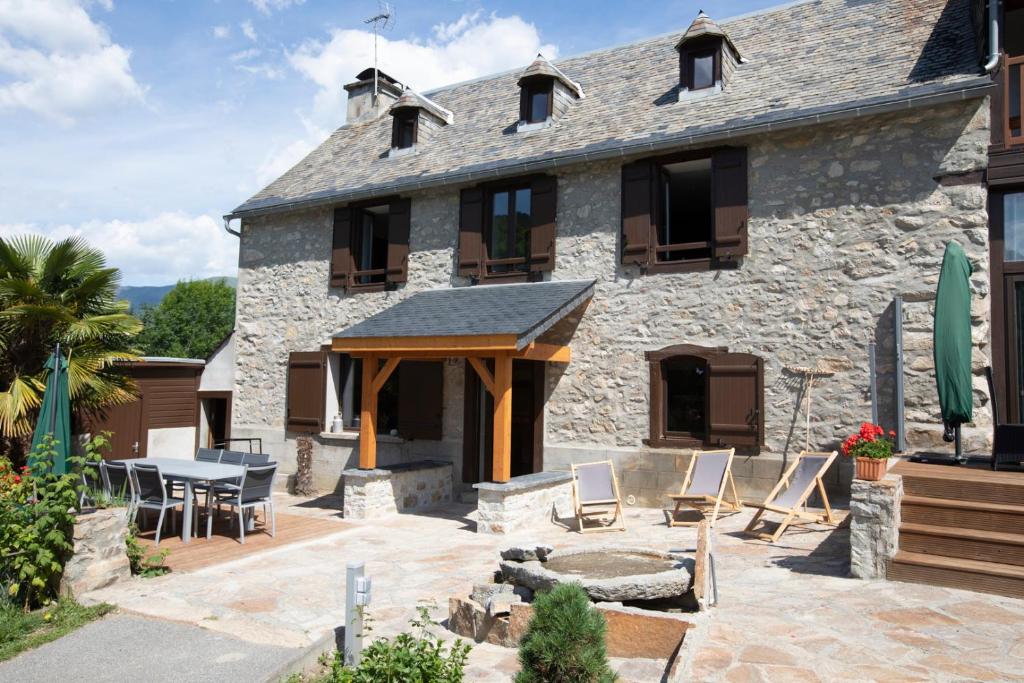 a stone house with a patio and a table and chairs at Gîte d&#39;AURE. Classé en meublé 4 étoiles. 