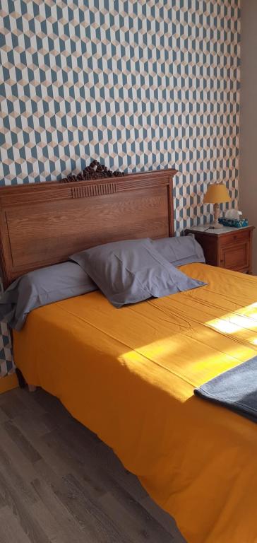 een slaapkamer met een geel bed en een geruite muur bij Chez sylvie in Soyaux