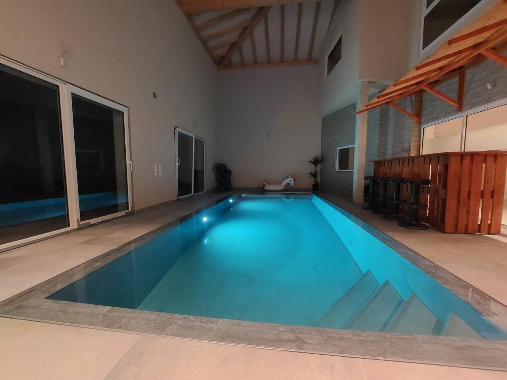 a large swimming pool with blue water in a room at Chambres de la Tuilerie in Saignelégier