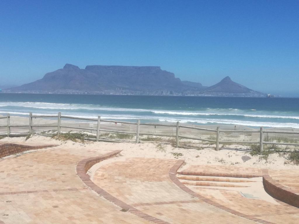 una playa de arena con una valla y el océano en Captain's Sea Cabin, en Ciudad del Cabo
