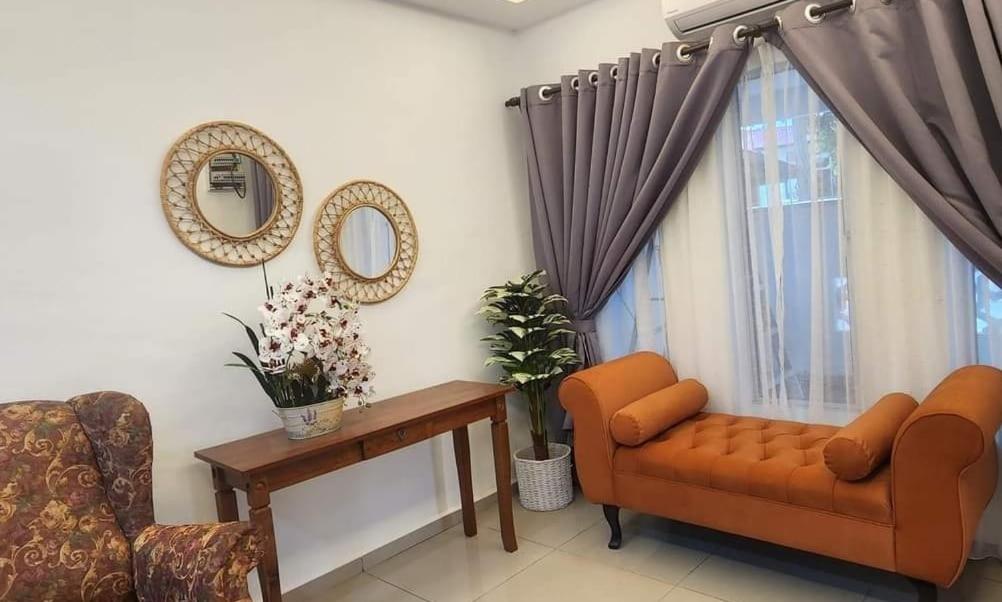 uma sala de estar com um sofá, uma cadeira e um espelho em AliyaRoseMuslim Homestay em Ayer Keroh