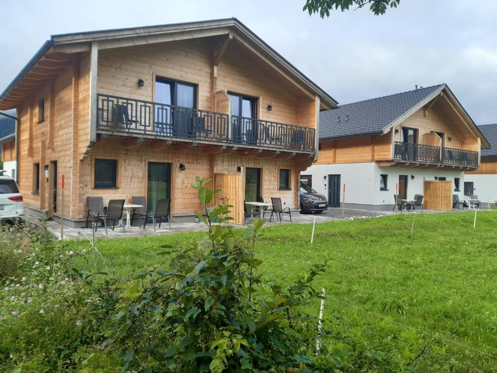 a house with a balcony and tables and chairs at Alpenchalets Nassfeld in Rattendorf