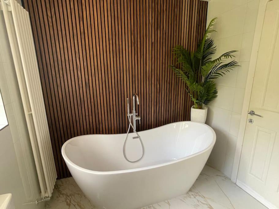 a white bath tub in a bathroom with a plant at Home in Wirral - Peaceful Contemporary Gem. in Wirral
