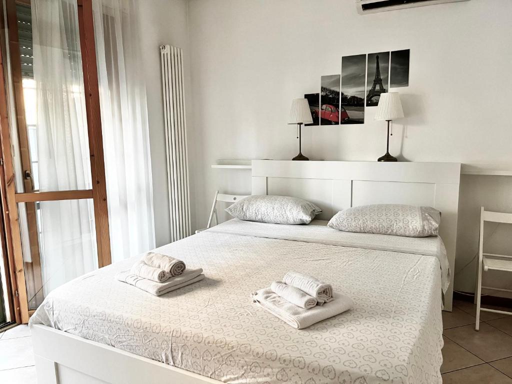 ボローニャにあるMaison Paradiso - Santa Viola Apartmentの白いベッドルーム(ベッドにタオル2枚付)