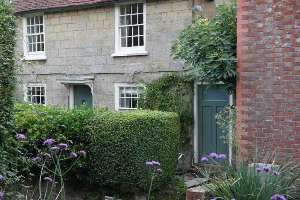 a brick house with a green door and a hedge at IVY COTTAGE in Pulborough