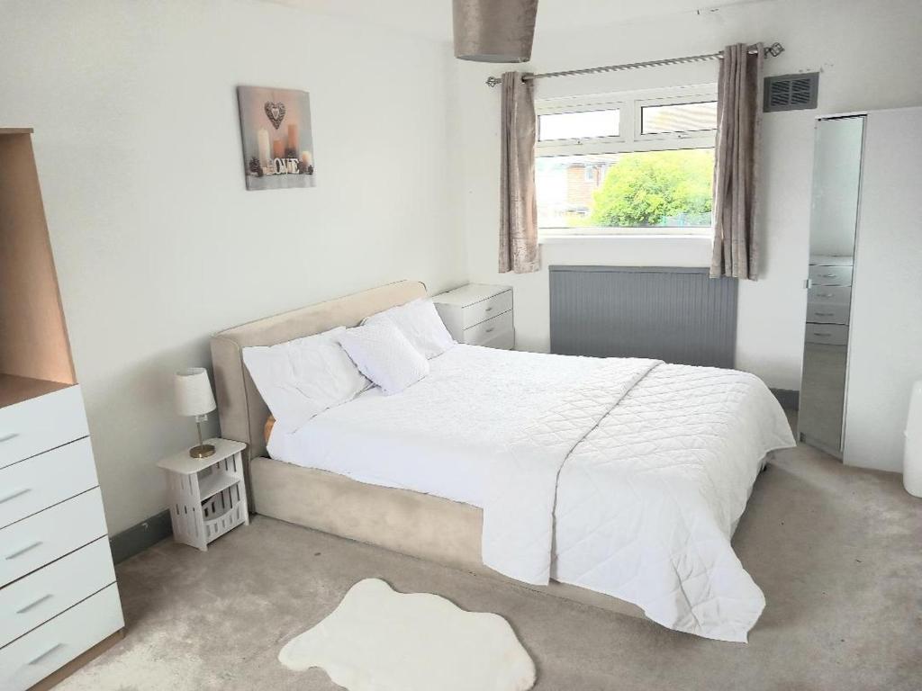 a white bedroom with a white bed and a window at House of Shiloh in Sheffield