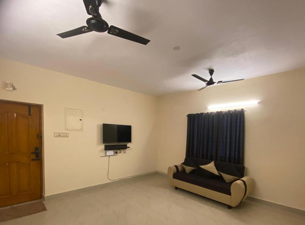 a living room with a ceiling fan and a couch at The waves in Chennai