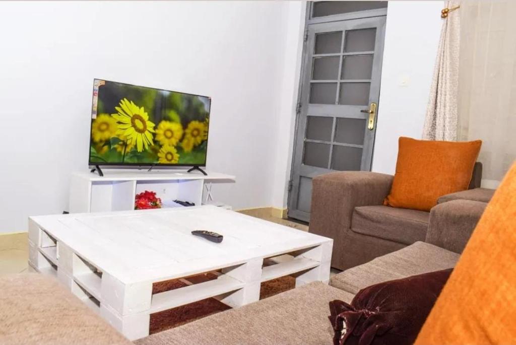 a living room with a white coffee table and a tv at Lighthomes31 in Thika
