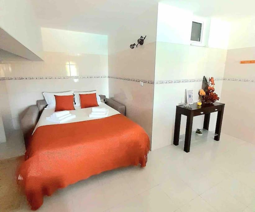 a bedroom with a bed with an orange blanket and a table at Paradise House Ground floor apartment in Villa with private pool and private garden in Abrantes
