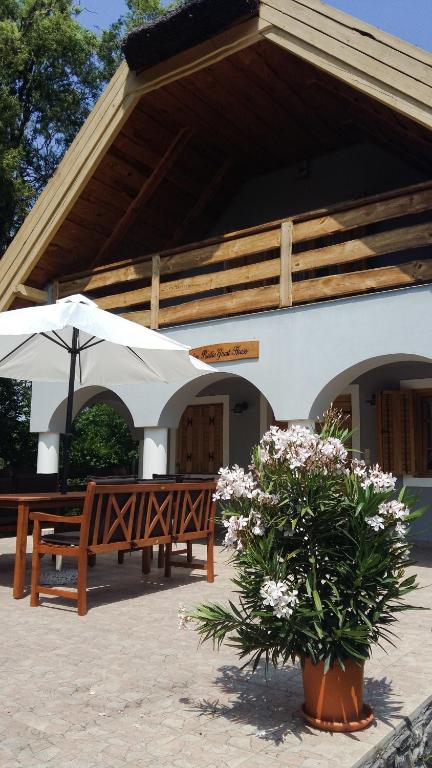 two benches and umbrellas in front of a building at Balaton Rustic Guesthouse in Badacsonytördemic