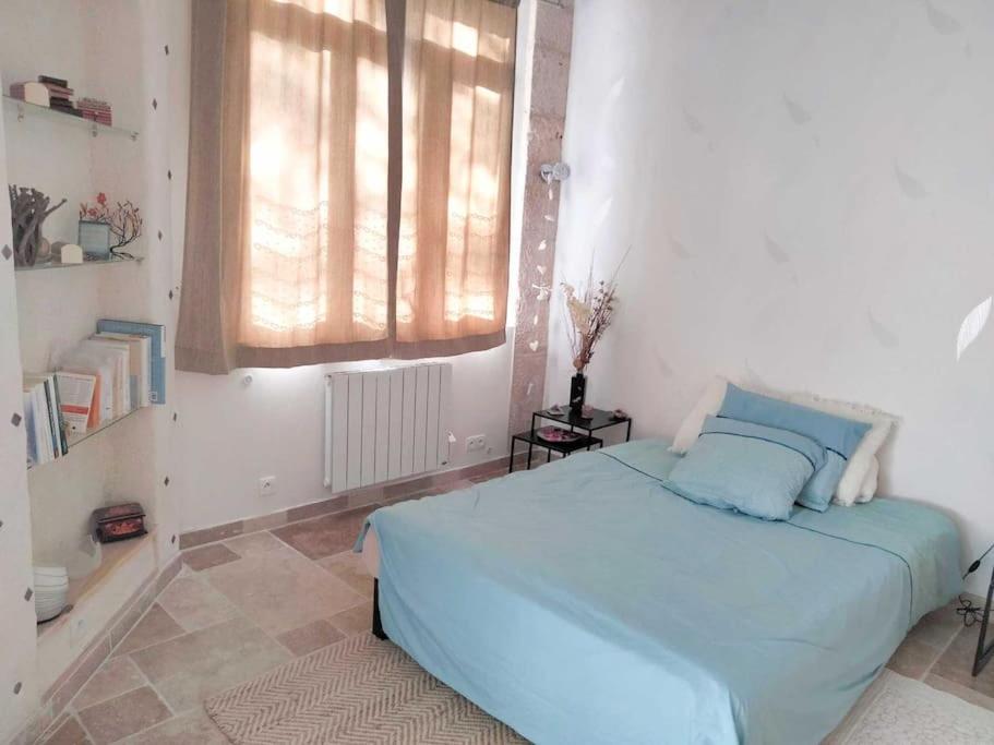 a bedroom with a blue bed and a window at Appartement au rez-de-chaussée in Souillac