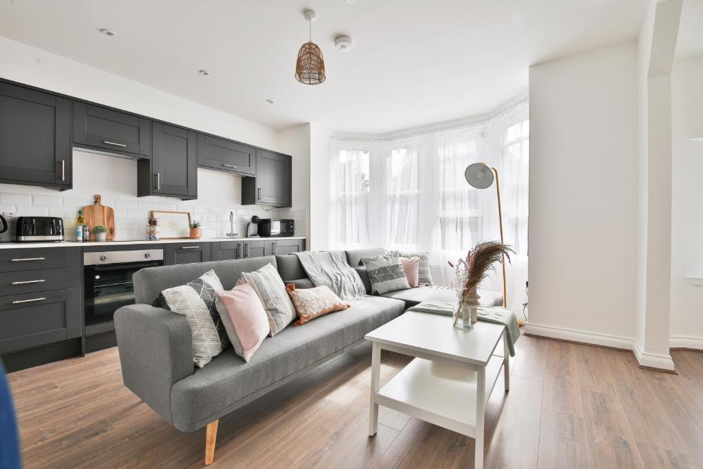 uma sala de estar com um sofá cinzento e uma cozinha em StayRight Spacious Apartments with Private Parking- 15-Minute Stroll to Town Centre em Cardiff