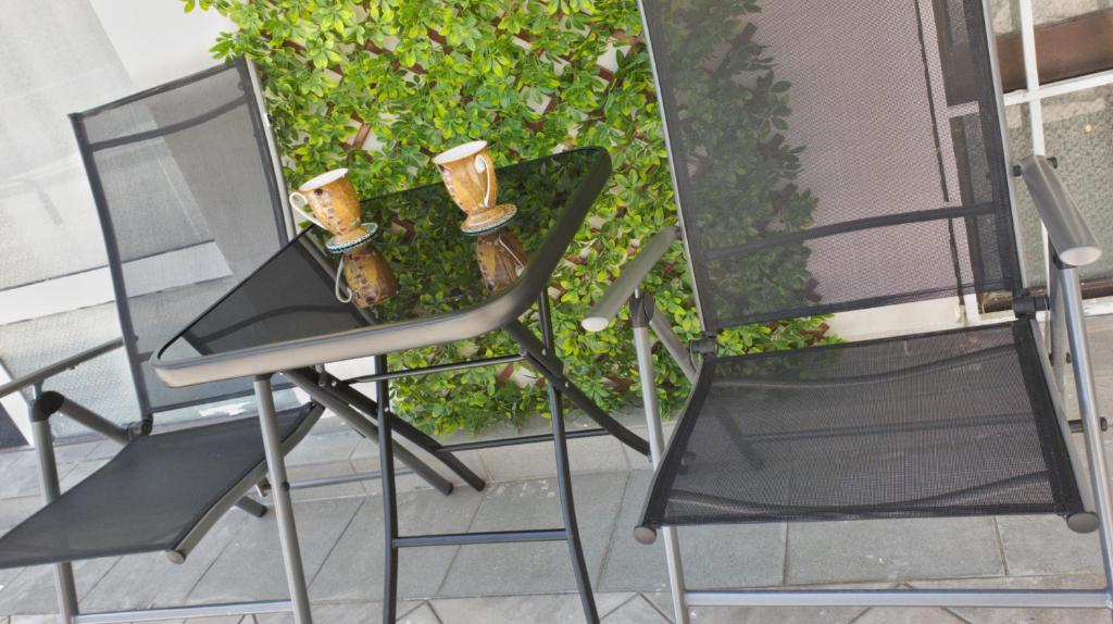 two chairs and a table with two vases on it at Cozy studio near the park with huge verandah. in Veliko Tŭrnovo