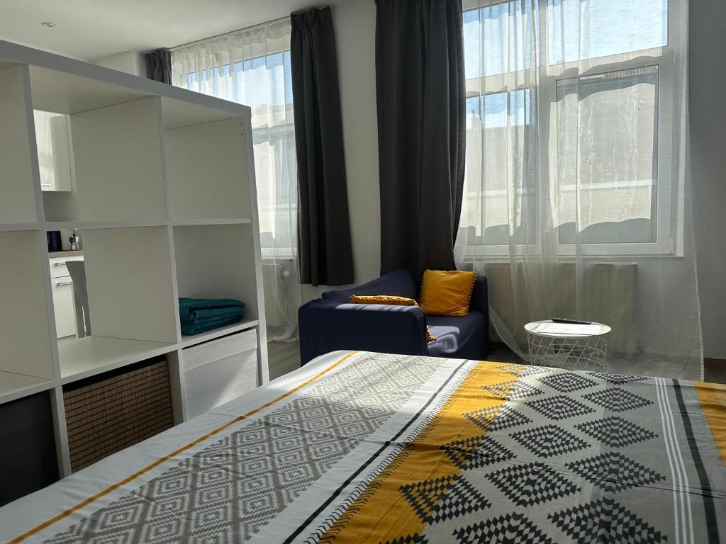 a bedroom with a bed and a chair and a window at Sofieflat - Wallifornie in Charleroi